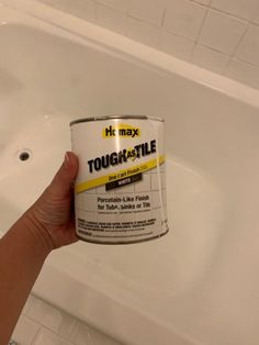 a hand holding a can of tough - style paint in front of a bathtub