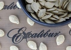 a bowl filled with pumpkin seeds sitting on top of a table next to an inscription