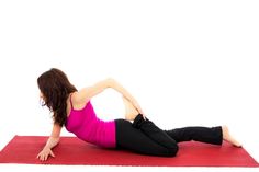 a woman in pink shirt and black pants doing exercises on red mat with white background