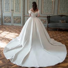 a woman in a white wedding dress is standing on the floor with her back to the camera