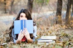 a woman laying on the ground with books covering her face