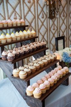 cupcakes are displayed on three tiered trays