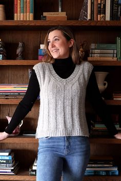 a woman standing in front of a bookshelf with her arms out and smiling