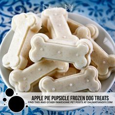 some dog treats are in a bowl on a blue and white tablecloth with the words apple pupple frozen dog treats