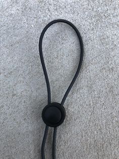 a black cord attached to a phone on the ground with an earphone plugged into it