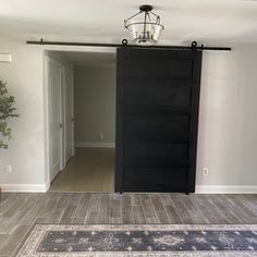 an empty room with a black door and rug on the floor