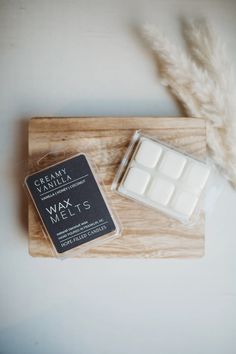 wax cubes are sitting on a wooden tray next to some pamy white flowers