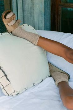 a woman laying on top of a bed with her feet propped up against a pillow