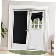 an open white door with black curtains on the window sill and green rug in front of it