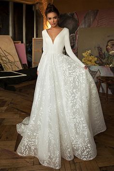 a woman in a white wedding dress standing on a wooden floor with her hands on her hips