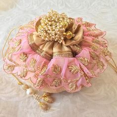 a pink and gold purse sitting on top of a white cloth covered table next to pearls