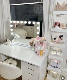 a white vanity with lights on it in front of a window and a chair next to it