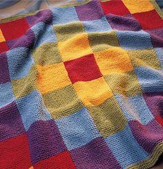 a multicolored blanket laying on top of a bed