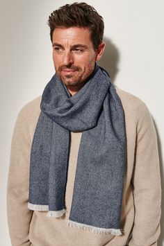 a man wearing a blue scarf standing in front of a white wall