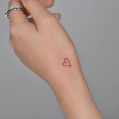 a woman's arm with a small red heart tattoo on the left side of her wrist