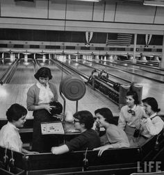 an old black and white photo of people in a bowling alley