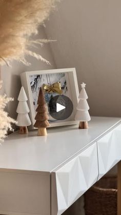 a white table topped with christmas trees and a small wooden tree on top of it