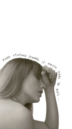 a woman holding her head in front of her face with words written on the wall behind her