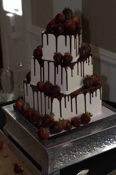 a triple layer cake with strawberries and chocolate drizzled on the top