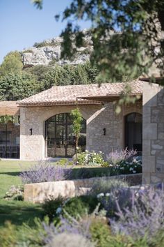 the house is surrounded by greenery and lavenders, with mountains in the background