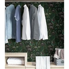 three shirts hanging on the clothes rack in front of a floral wallpapered wall