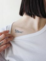 a woman with a small cross tattoo on her upper back neck and shoulder, looking at the camera