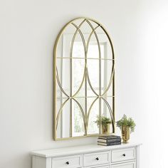 a white dresser topped with a mirror next to a window