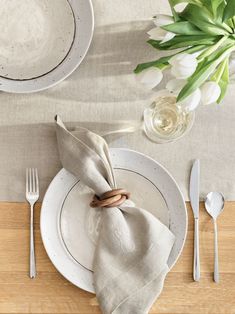 a place setting with napkins, silverware and tulips