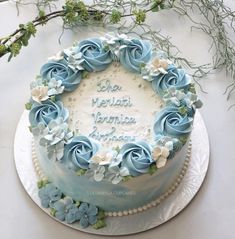 a cake with blue frosting and flowers on top is sitting on a white table