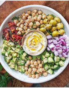 a white bowl filled with lots of different types of food on top of a wooden table