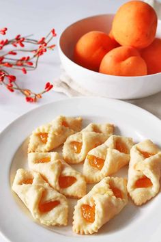 several pieces of pie on a plate next to some oranges and a bowl of fruit