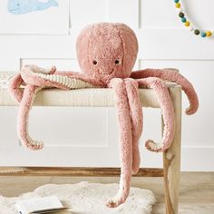 an octopus stuffed animal sitting on top of a wooden bench next to a white rug