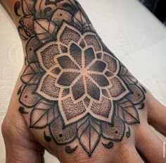 a person's hand with a black and white tattoo design on the middle of it