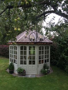 a small white gazebo sitting on top of a lush green field