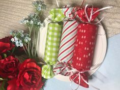 three wrapped presents are sitting on a plate next to red roses and baby's breath