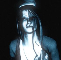 a woman with long hair wearing a hat and looking at the camera while standing in front of a black background