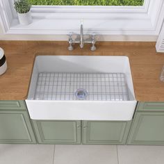 a white kitchen sink sitting on top of a wooden counter next to a green cabinet