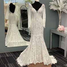 a white wedding dress is on display in front of a mirror and mannequin