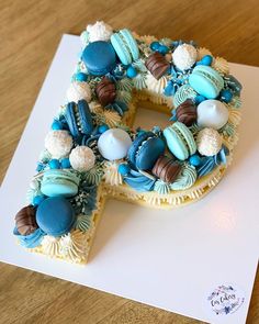 a cake shaped like the letter g on top of a white paper with blue and brown decorations