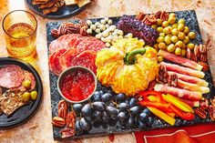 an assortment of meats and vegetables on a platter next to two glasses of beer