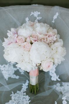 a bouquet of white flowers sitting on top of a table covered in sheer net material