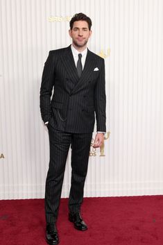 a man in a suit and tie on the red carpet at an awards event with his hands in his pockets