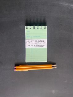 a notepad and two pencils sitting on top of a blackboard with the words paper to post written on it