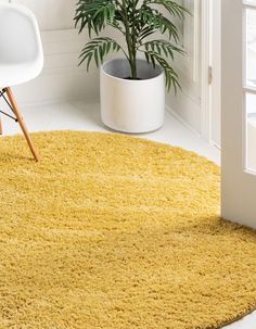 a bright yellow rug in the corner of a room with a chair and potted plant