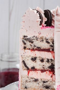 a close up of a slice of cake with oreo cookies on top and pink frosting