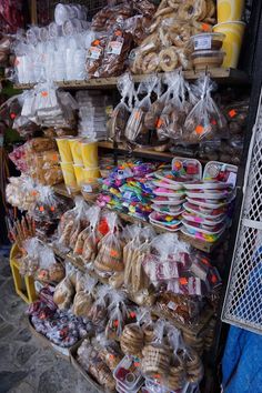 there are many different types of breads on the shelves in this market stall, including bagels and muffins