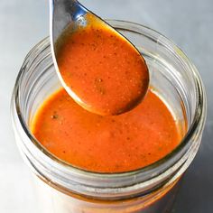 a spoon full of sauce on top of a jar