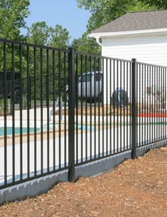 a black metal fence next to a white house with a car parked in the driveway