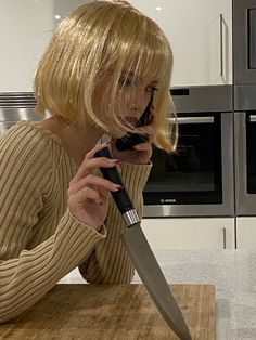 a woman holding a knife on top of a wooden cutting board