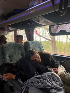 people sleeping in the back of a bus with their heads resting on each other's backs